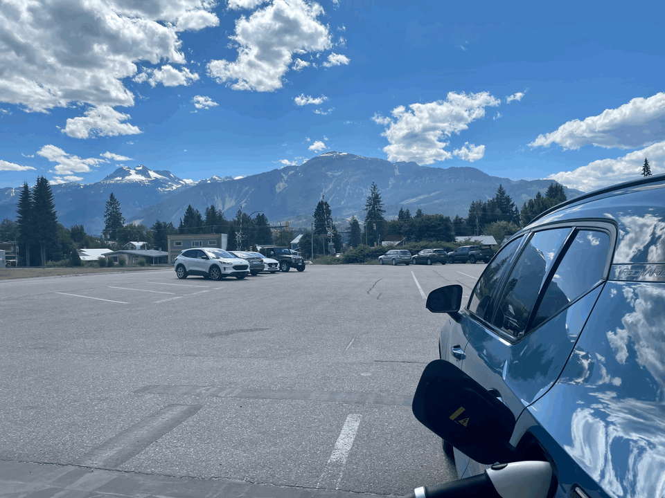 View of the mountains in Revelstoke, BC in the background while an EV charging is shown in the foreground.